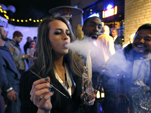 Jovem fuma maconha em uma festa de Réveillon que celebra o início da venda da droga em Denver